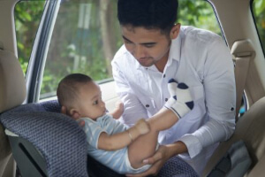 photo of man putting a baby in a car seat