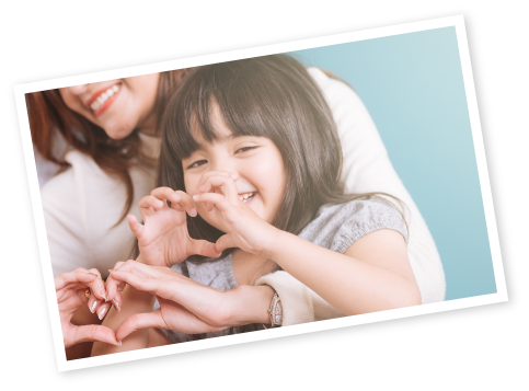 Photo of woman holding child who is making a heart shape with her hands